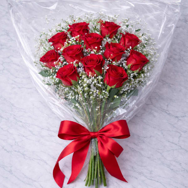 Bouquet of red roses wrapped in clear plastic with a red ribbon