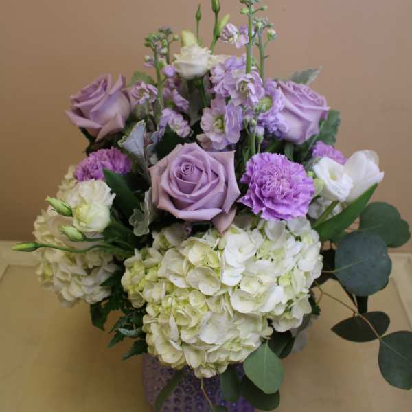 Lavender roses and white hydrangeas in a purple vase