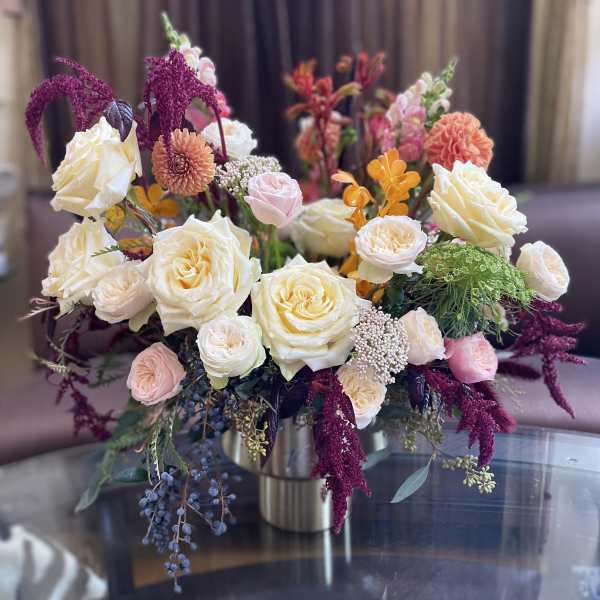 Mixed bouquet of cream, pink, and orange flowers in a metal vase