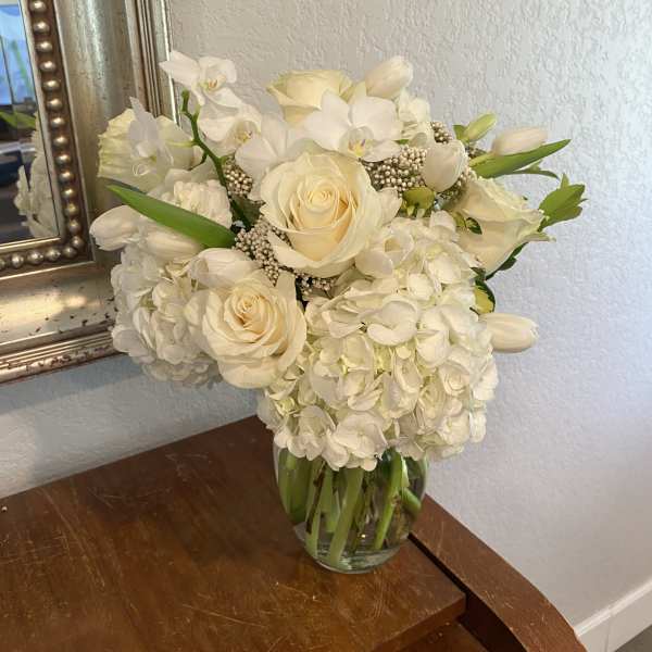 White roses and hydrangeas arranged in a clear glass vase