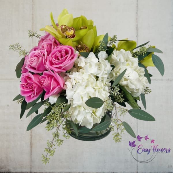 Pink roses and white hydrangeas with green orchids in a glass vase