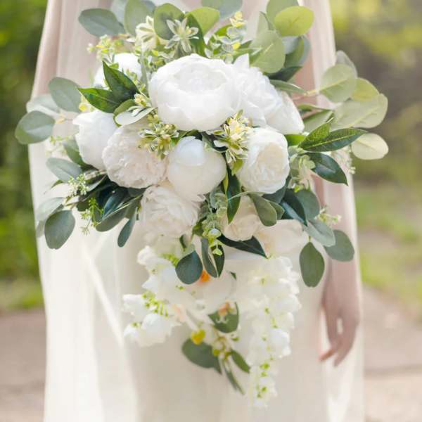 Cascading bridal bouquet of white flowers with lush green foliage accents