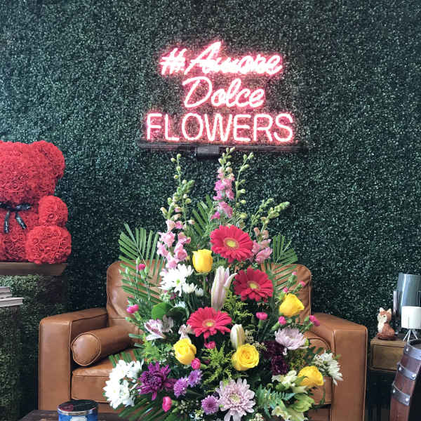 Mixed flower arrangement in a white basket on a table