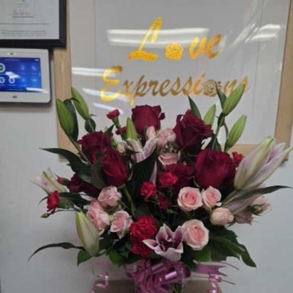 Bouquet of red and pink roses with lilies in a glass vase