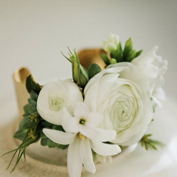 White ranunculus and small white blossoms arranged in a compact bouquet
