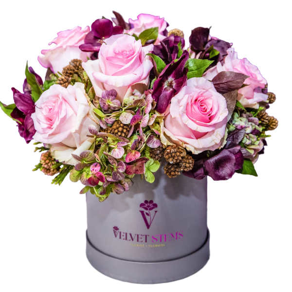 Pink roses and purple flowers arranged in a gray hat box