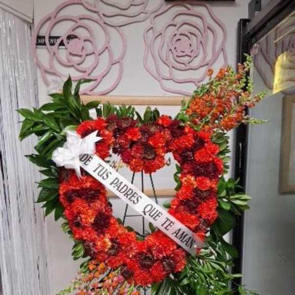 Heart-shaped red floral standing wreath on an easel with a white ribbon