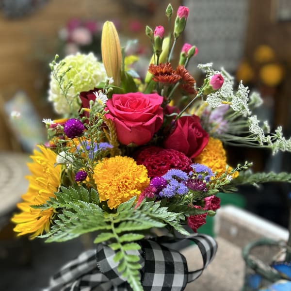 Colorful mixed bouquet with roses, sunflowers, and a black-and-white ribbon