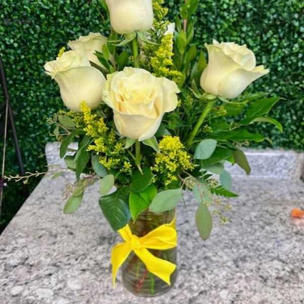 White roses in a glass vase with a yellow ribbon