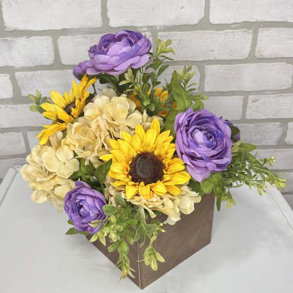 Purple and yellow flowers arranged in a brown box