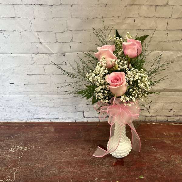 Pink roses in a white vase with a pink ribbon