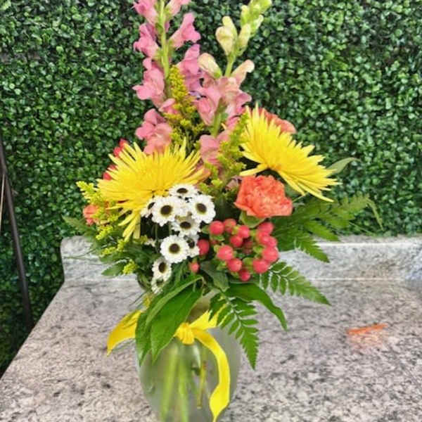 Mixed bouquet in a glass vase with yellow, pink, white, and coral flowers