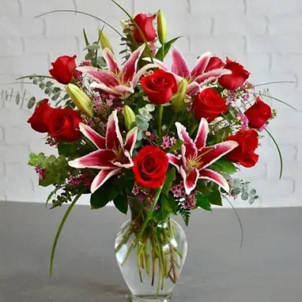 Red roses and pink lilies arranged in a clear glass vase