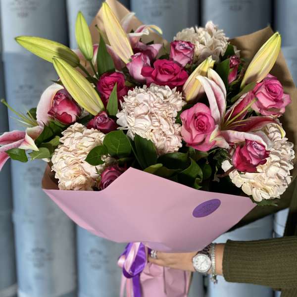 Bouquet of pink roses and pale lilies wrapped in pink paper