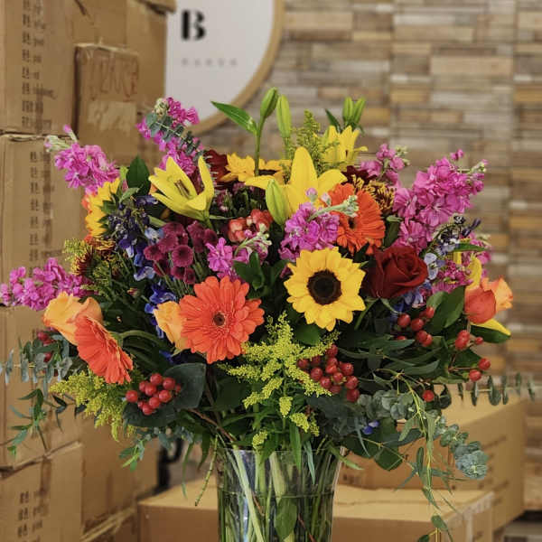 Colorful mixed bouquet in a clear glass vase with lilies and sunflowers