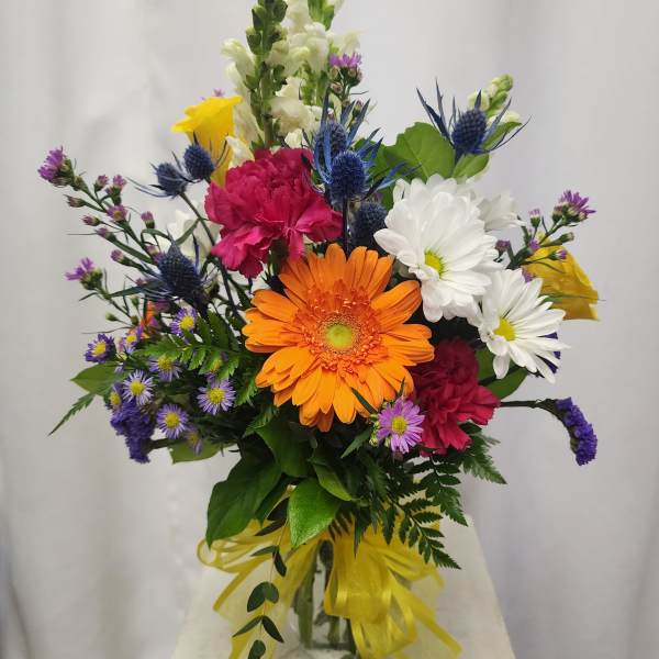 Mixed bouquet with orange gerbera daisies, white daisies, and pink carnations in a glass vase