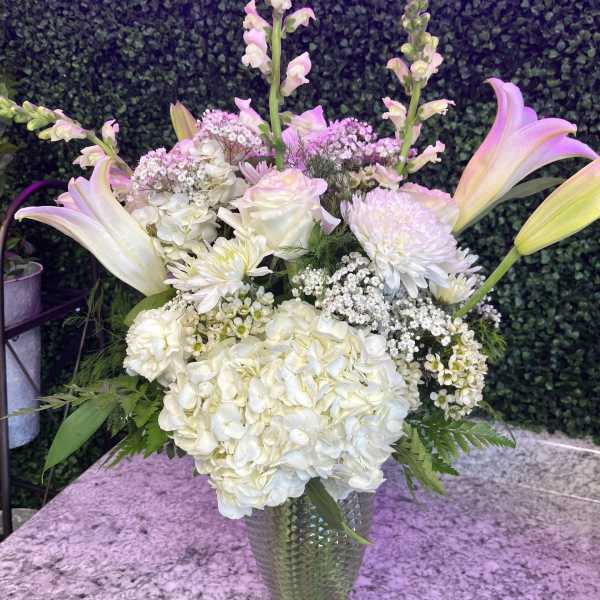 White floral arrangement with lilies and hydrangeas in a glass vase