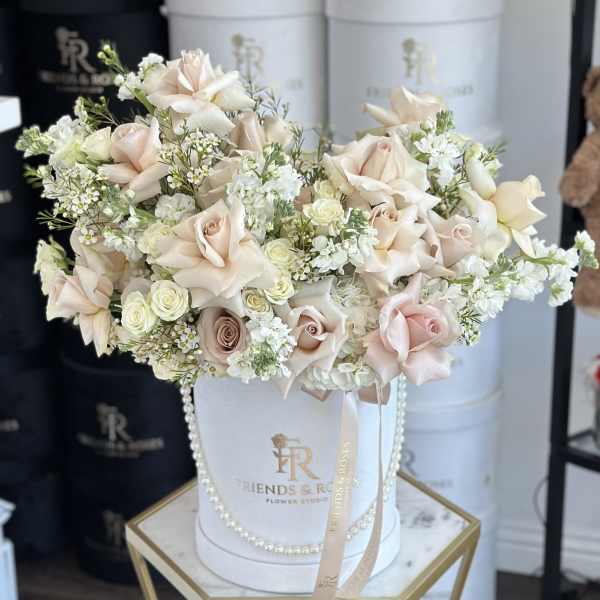 Blush and white rose arrangement in a white hatbox with ribbon