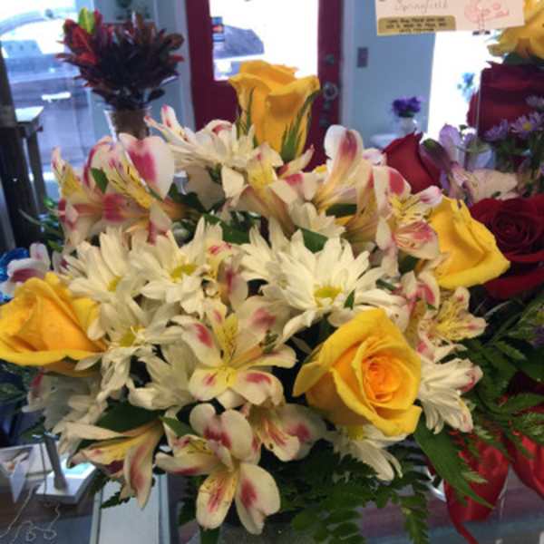 Bouquet of yellow roses, white daisies, and pink-speckled lilies