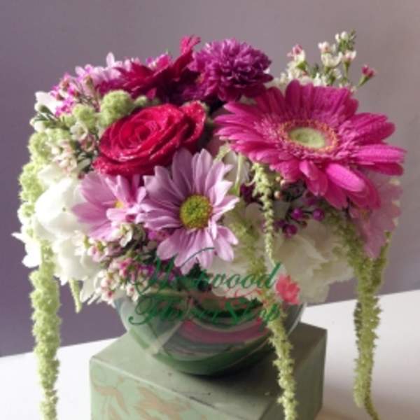Pink and white mixed bouquet in a glass vase on a box