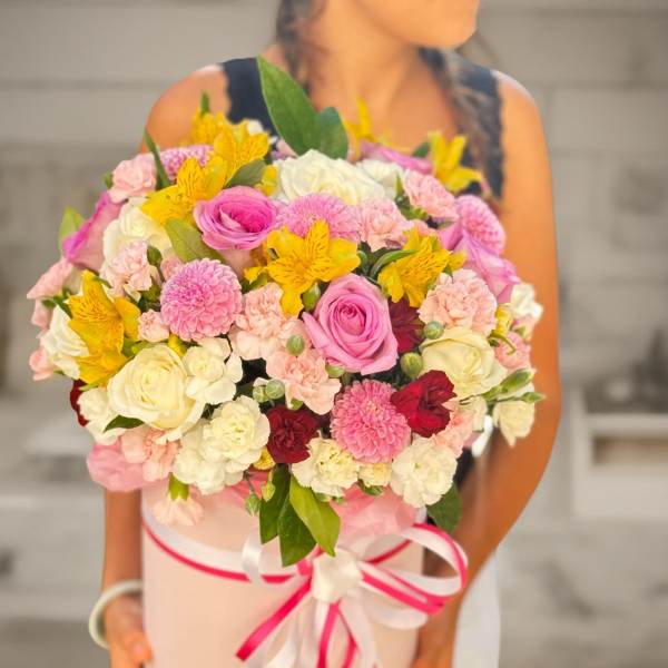 Large bouquet of pink, white, yellow, and red flowers in a pink hat box
