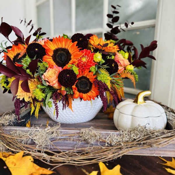 Bright autumn floral arrangement in a white bowl beside a white pumpkin decor piece