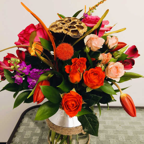 Mixed bouquet of orange, pink, and purple flowers in a glass vase