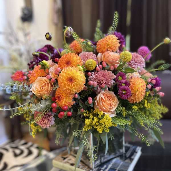 Colorful bouquet of orange, pink, and purple flowers in a glass vase