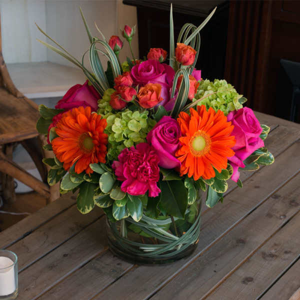 Bright mixed bouquet in a glass vase with orange daisies and pink roses