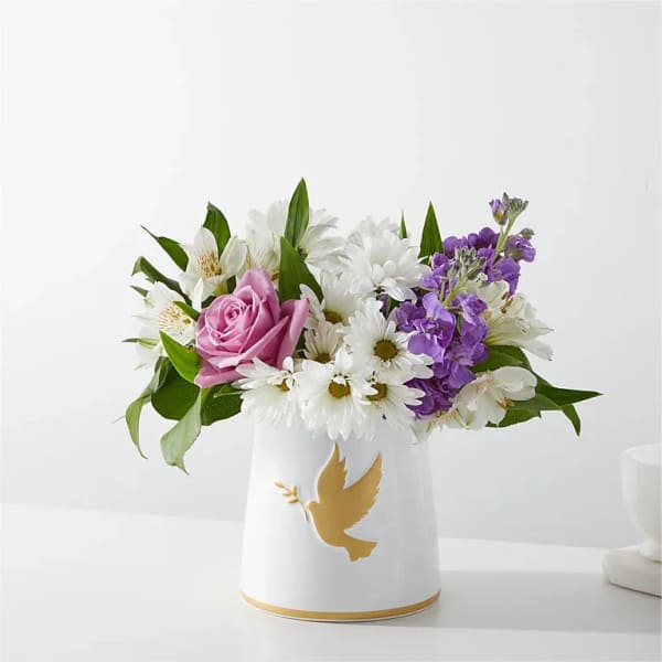 Pink rose and white daisy bouquet in a white vase with a gold dove design