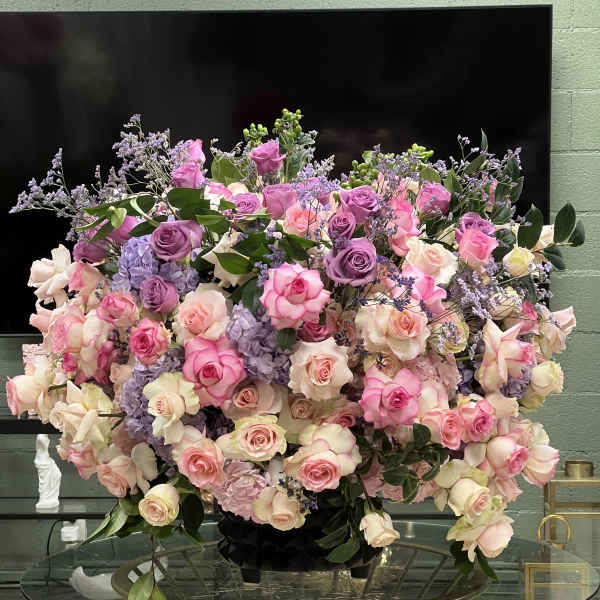 Large arrangement of pink, lavender, and cream roses in a black vase