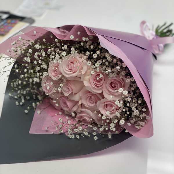 Bouquet of pink roses with white baby's breath in pink and black wrap