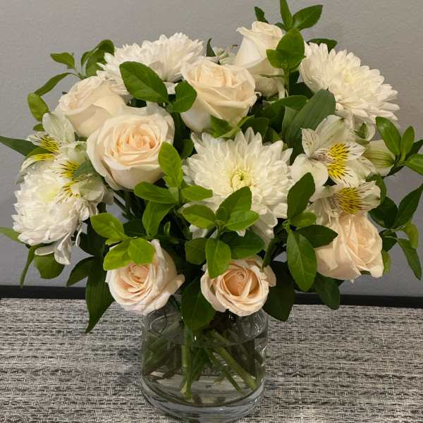 Bouquet of white roses and white chrysanthemums in a clear glass vase