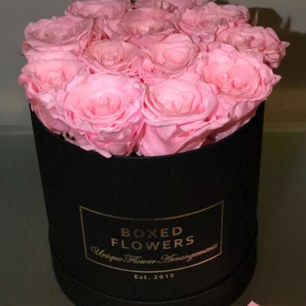 Pink roses arranged in a black round box