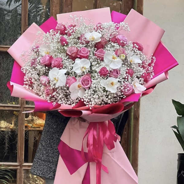 Large bouquet of pink roses and white orchids wrapped in pink paper