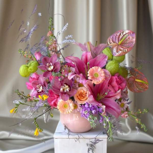 Pink and purple floral arrangement in a pale pink vase