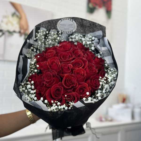 Bouquet of red roses with white baby's breath in black wrapping