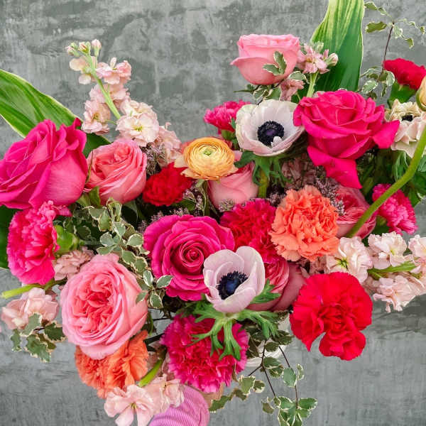 Handheld bouquet of pink and red roses with mixed blooms