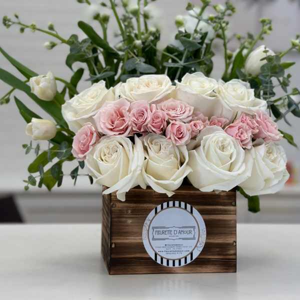 White and blush roses arranged in a wooden box
