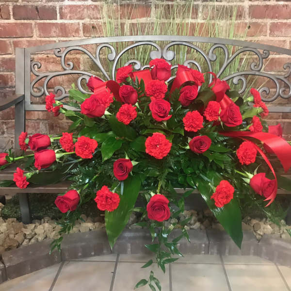 Red rose and carnation arrangement on a bench
