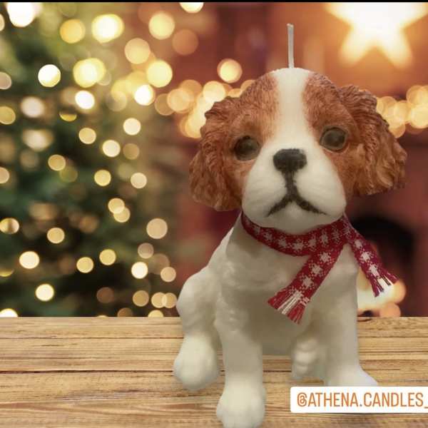 Dog-shaped candle with a red scarf on a wooden surface