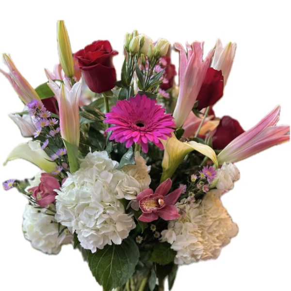 Mixed bouquet of roses, lilies, gerbera daisies, and hydrangeas in a glass vase