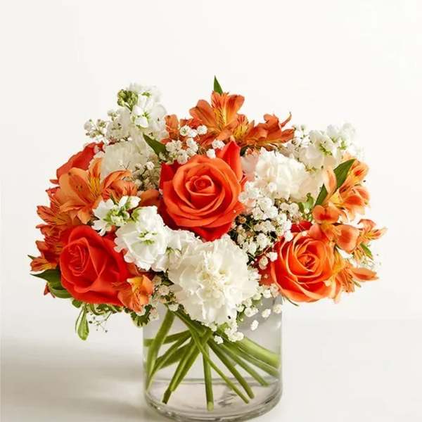 Orange and white flower arrangement in a clear glass vase