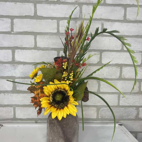 Sunflower arrangement in a gray vase with autumn foliage and berries