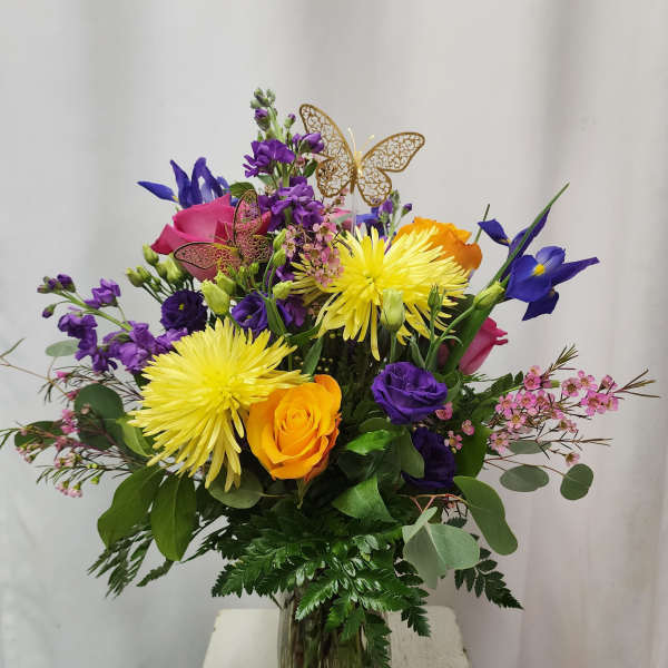 Mixed bouquet in a glass vase with yellow, purple, pink, and orange flowers