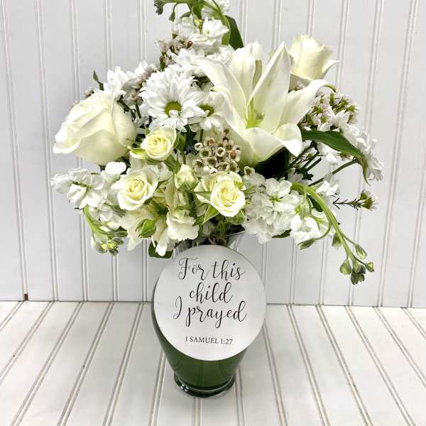 White floral arrangement in a glass vase with a memorial plaque