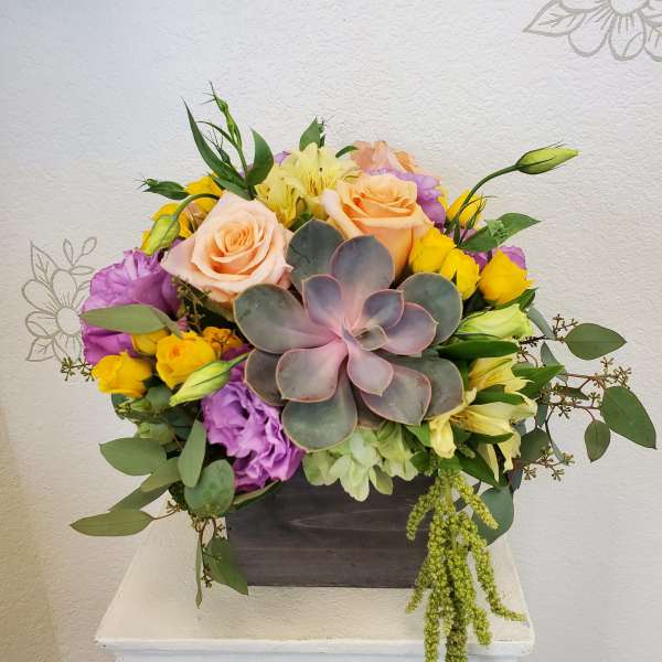 Mixed bouquet with roses, lisianthus, and a succulent in a dark box