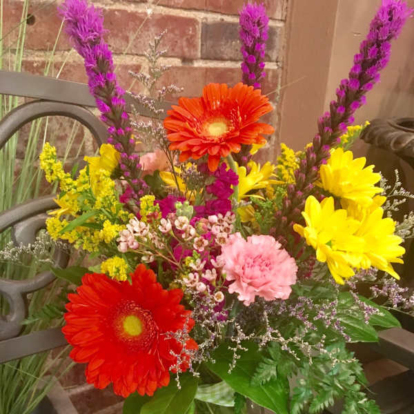 Colorful mixed bouquet in a glass vase with gerbera daisies and carnations