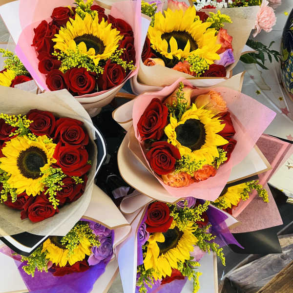 Bouquets of sunflowers and red roses wrapped in pastel paper