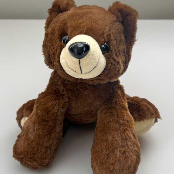 Brown plush teddy bear seated on a white surface